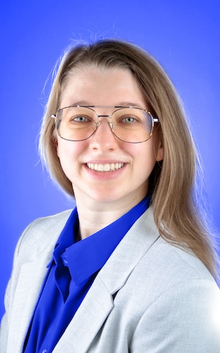 Michelle Blanchette smiling in professional attire on a bright blue background